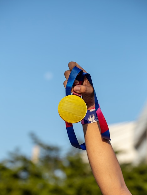 Photo main tenant la médaille sur fond de ciel, gagnant et concept réussi