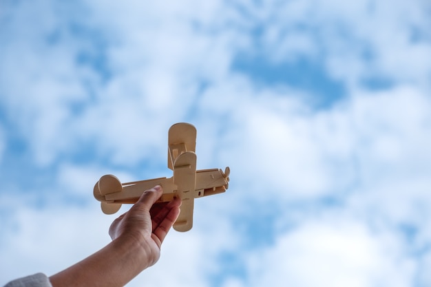 Une main tenant et montant un avion en bois en fond de ciel bleu