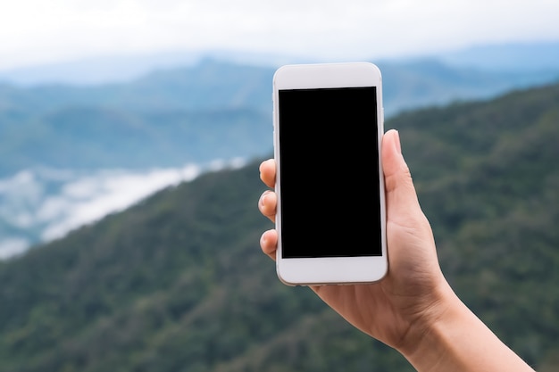 main tenant et montrant un téléphone intelligent blanc avec écran de bureau vide