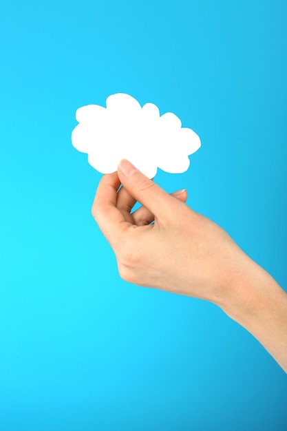 Main tenant un nuage de papier sur fond bleu Concept de cloud computing