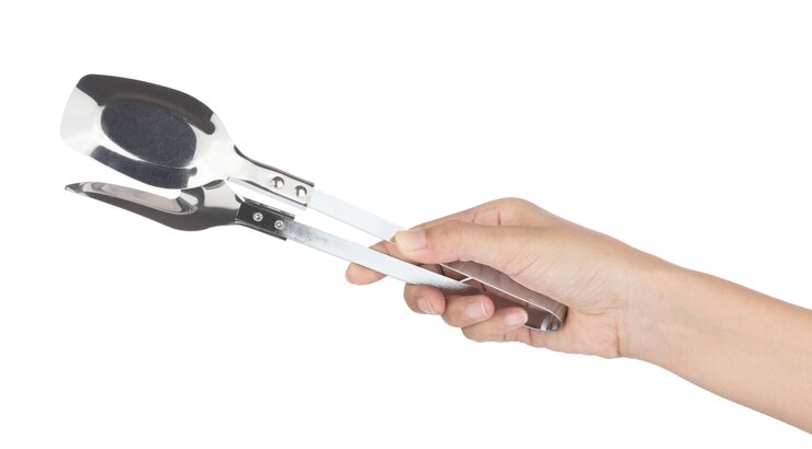 Photo main tenant des outils d'ustensiles de cuisine en acier inoxydable isolés sur fond blanc.