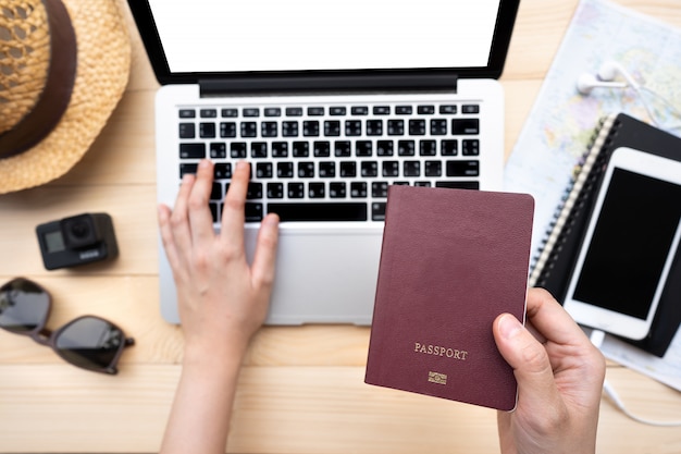 Main tenant un passeport avec une carte et un ordinateur portable pour la planification de voyager. Voyager vacances voyage vacances.