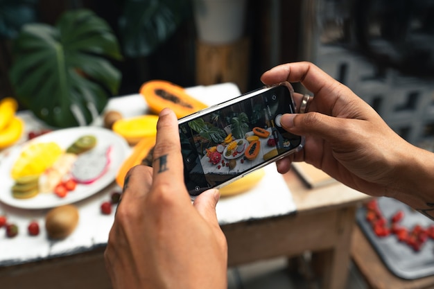 Main tenant une photo de fruits sur la table