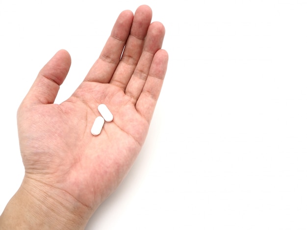 Main tenant une pilule blanche isolée sur fond blanc.