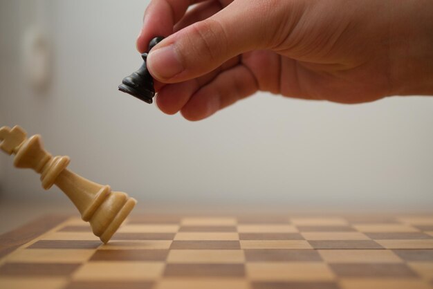 La main tenant un pion noir alors qu'il frappe le roi blanc dans une partie d'échecs.