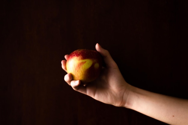 Une main tenant une pomme sur un fond sombre Salvador Bahia Brésil