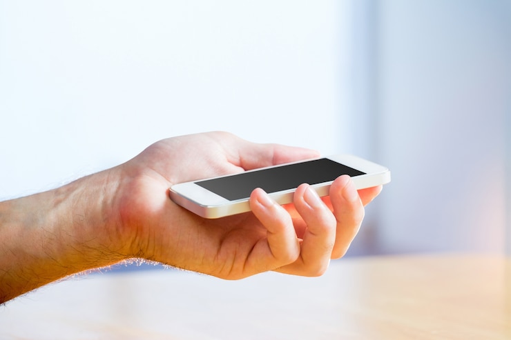 Photo main tenant un smartphone blanc