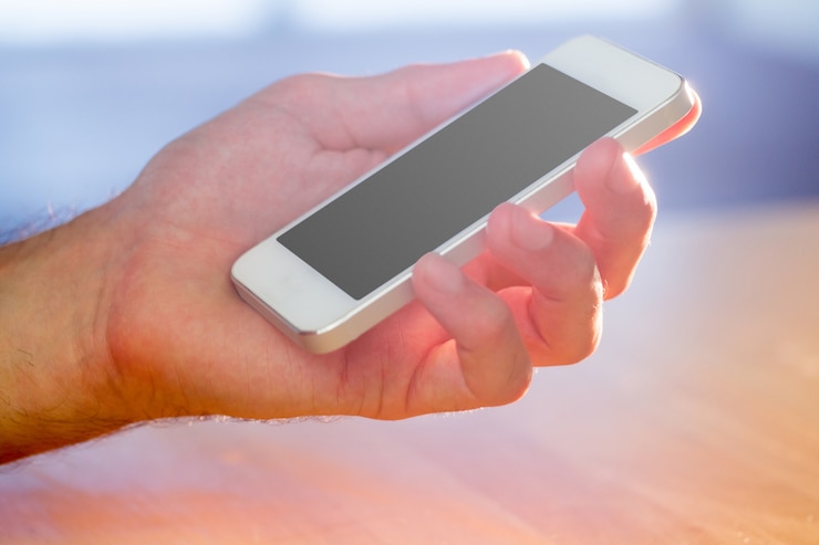 Photo main tenant un smartphone blanc