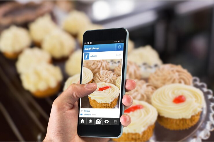 Photo main tenant un smartphone contre une variété de pâtisseries au café