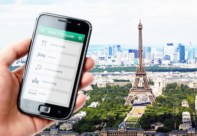 Main tenant un smartphone avec un guide de la ville de Paris