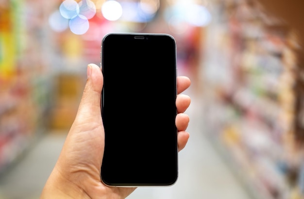 Main tenant un smartphone maquette noir et un arrière-plan flou avec un téléphone bokeh sur la main pour la présentation du produit et des activités concept de style de vie