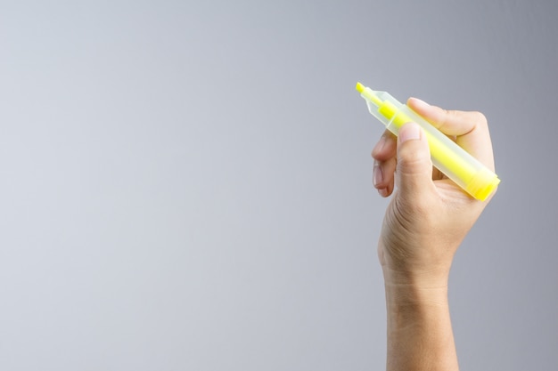 Main tenant le surligneur jaune pour écrire un marqueur de mot couleur