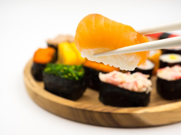 Main tenant des sushis avec des baguettes Sushi sur fond de plaque en bois Cuisine japonaise