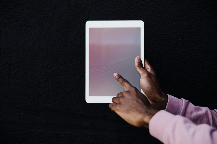 Photo main tenant une tablette numérique sur fond noir