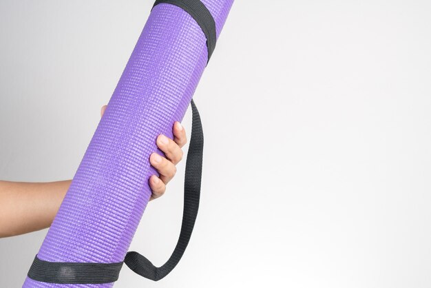 Main tenant un tapis de yoga, accessoire d&#39;exercice et de remise en forme