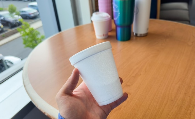 Une main tenant une tasse de café avec un verre qui dit "café" dessus