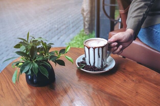 Main tenant une tasse de chocolat chaud sur une table en bois au café