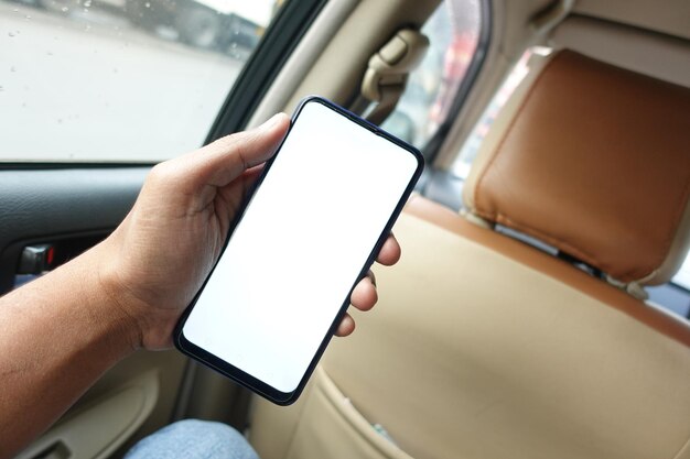 main tenant un téléphone intelligent avec écran vide dans une voiture