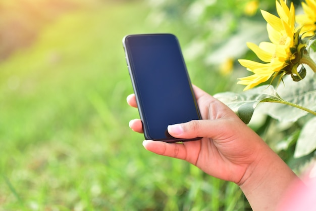 main tenant un téléphone intelligent avec fond de nature