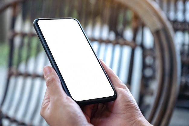 Main tenant un téléphone mobile noir avec écran blanc vierge à l'extérieur
