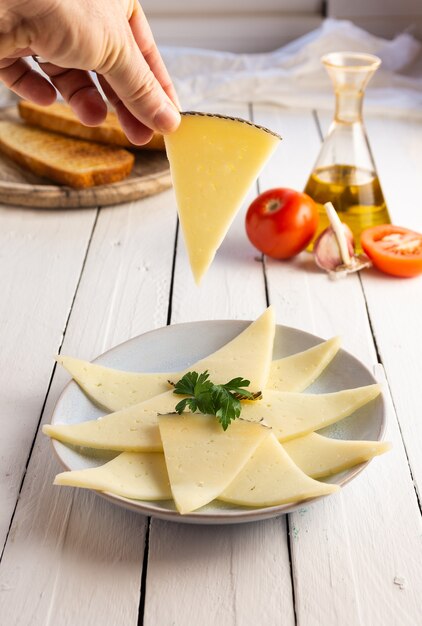 Main tenant une tranche de fromage, table en bois blanc