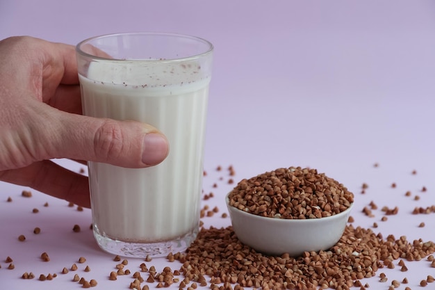 Une main tenant un verre de lait à côté d'un bol de lentilles.