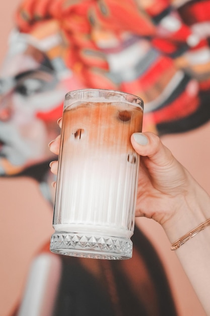 une main tenant un verre de lait avec un fond rose