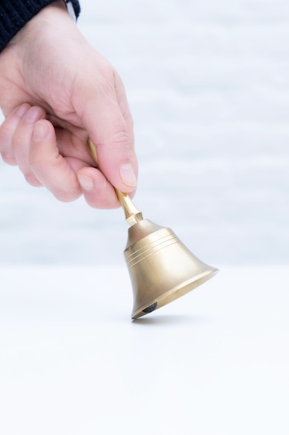 Main tenir la cloche dorée fond blanc copie espace directeur de l'école