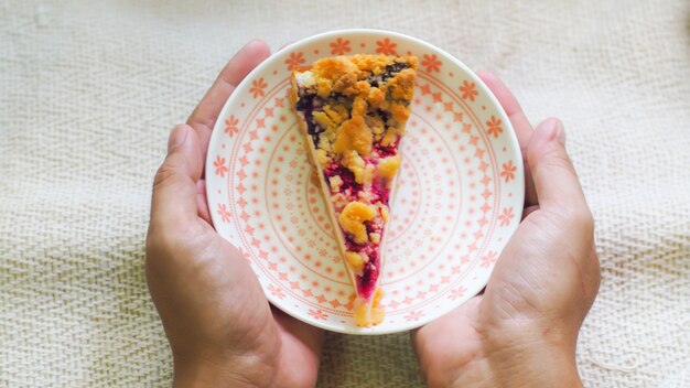 Main tenir le gâteau au fromage aux bleuets sur le petit-déjeuner du matin de la plaque