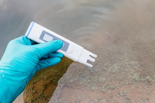 Photo main tenir le testeur de qualité de l'eau et prendre l'eau d'échantillonnage pour l'analyse