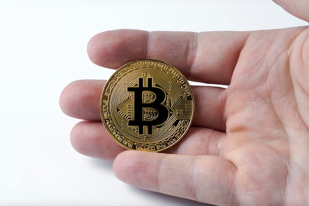 La main tient un bitcoin sur un fond blanc