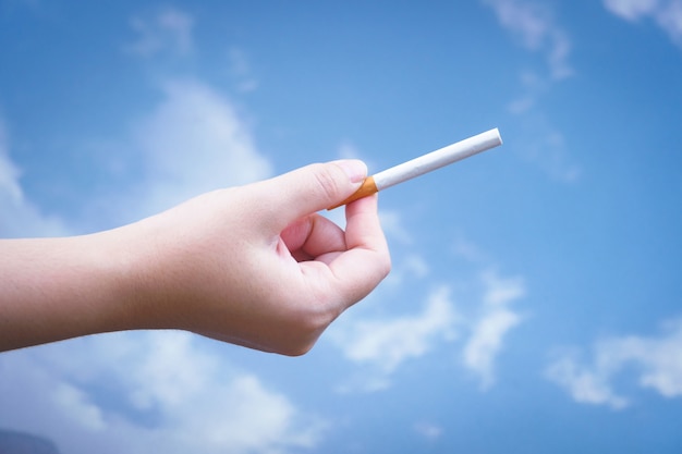 Main tient une cigarette sur fond bleu, ne pas fumer. Cesser du concept de dépendance.