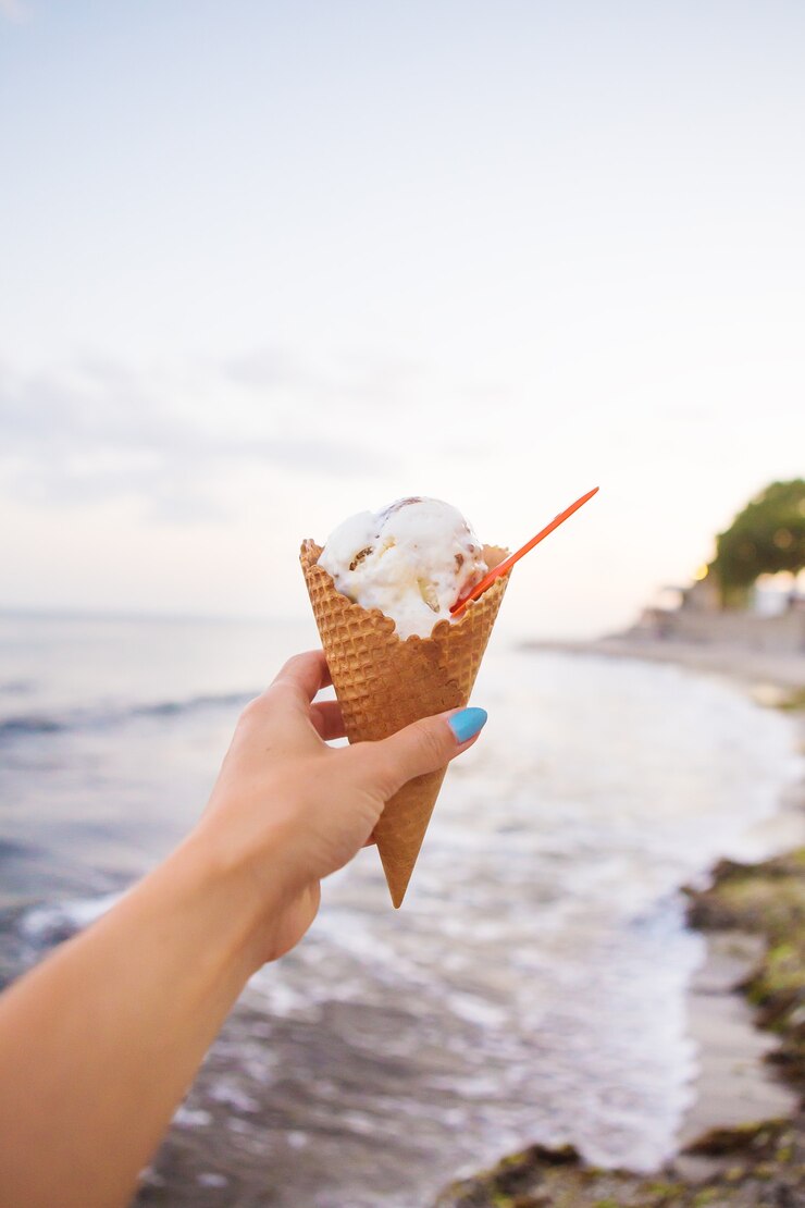 Une main tient une délicieuse crème glacée sur une plage d'été.