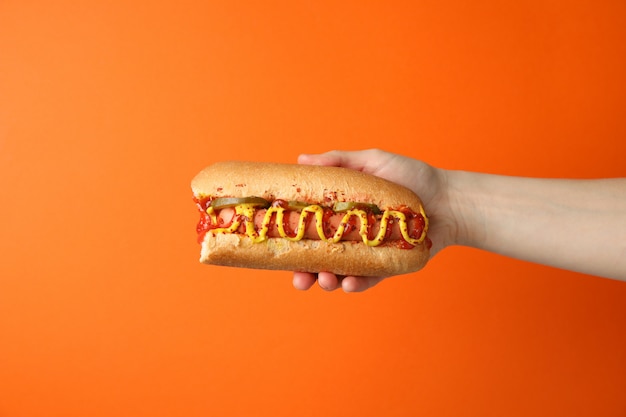 Main tient un délicieux hot-dog sur orange