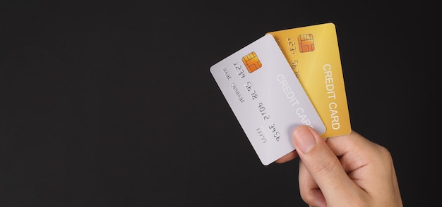 La main tient deux cartes de crédit Cartes de crédit couleur or et argent isolées sur fond noir