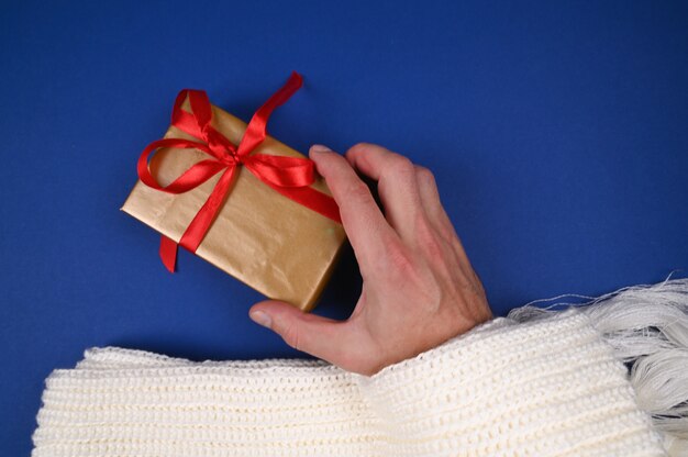 La main tient l'emballage cadeau sur fond bleu. photo de haute qualité