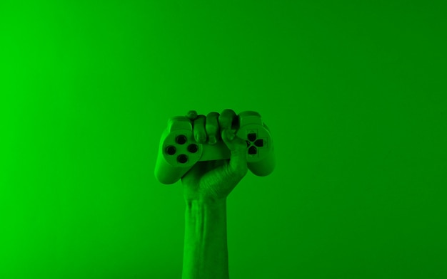 Main tient une manette de jeu avec une lumière holographique verte.