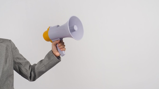 La main tient un mégaphone et une partie du corps porte un costume gris sur fond blanc.