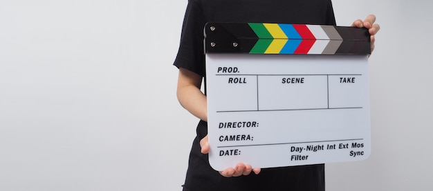 La main tient le panneau de clapet ou l'ardoise de film et se tient sur le fond blanc. il est utilisé dans la production vidéo et l'industrie cinématographique.