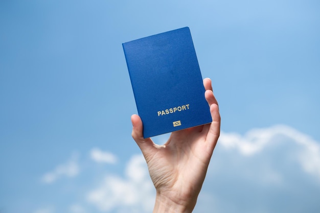 La main tient le passeport sur le fond du ciel bleu avec des nuages Concept de voyage