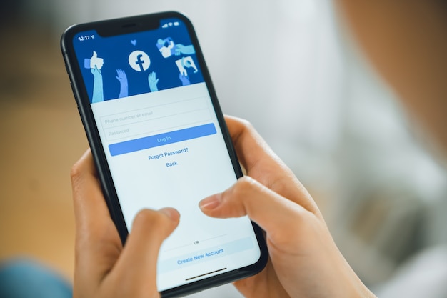 Main tient le smartphone et l'écran Facebook