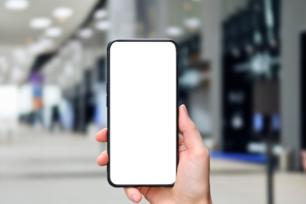La main tient un smartphone avec un espace de copie et l'arrière-plan de l'immeuble de bureaux.