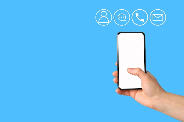 Une main tient un smartphone prêt à communiquer avec diverses icônes à proximité