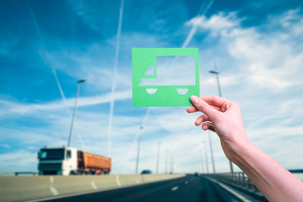 La main tient le symbole logistique vert contre l'autoroute