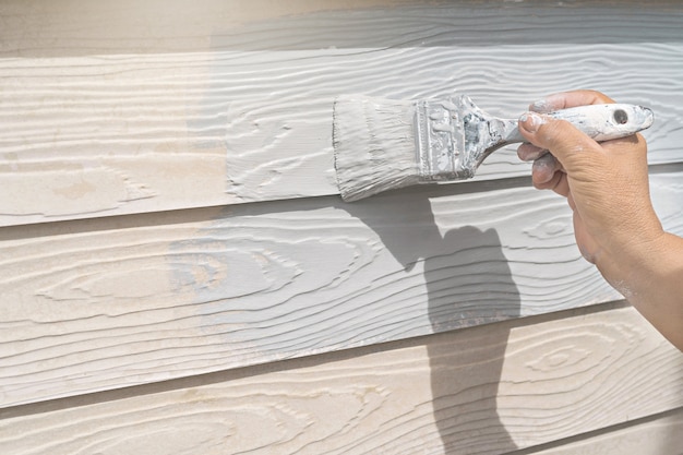 Photo main de travailleur peinture sur mur de bois maison neuve sur le chantier de construction.