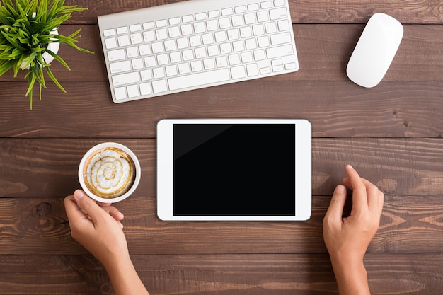 main en utilisant l&#39;écran blanc de la tablette blanche sur l&#39;espace de travail de la table