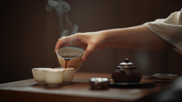 Une main versant une tasse de thé dans une tasse