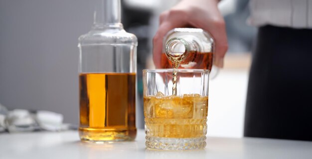 Une main verse une boisson alcoolisée brune dans un verre