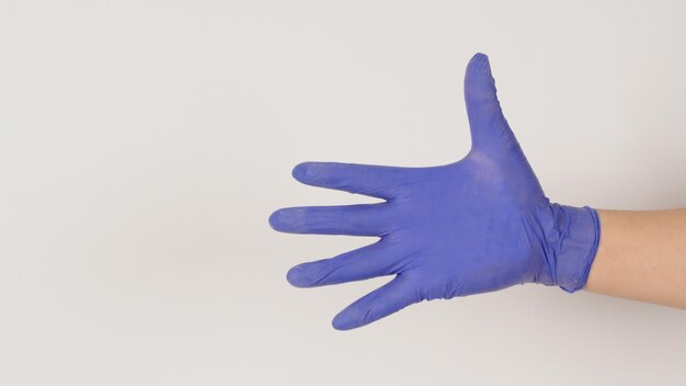 Main vide porter des gants en latex violet sur fond blanc