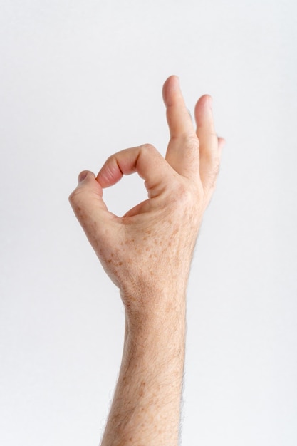 Photo main de vieil homme faisant un geste ok fond blanc